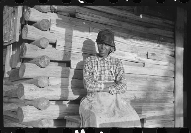 Woman sitting on the porch of a wood cabin, arms crossed