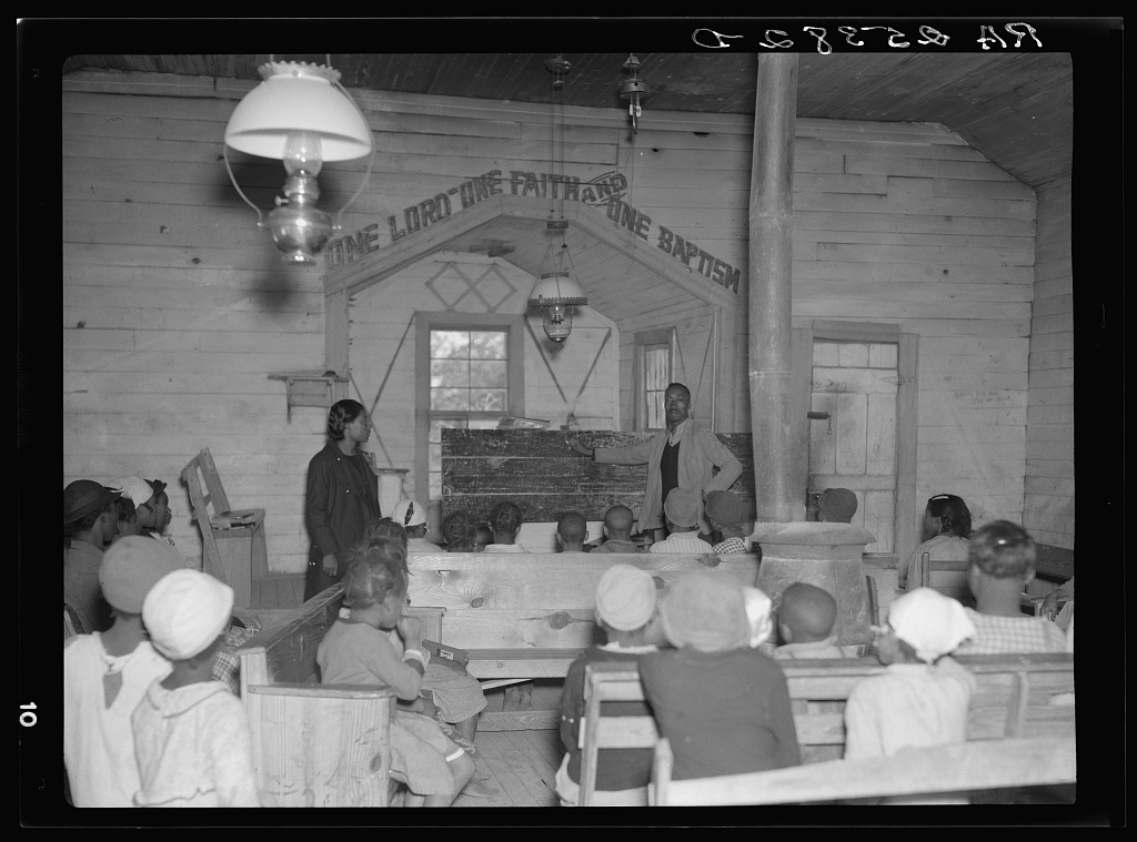 Children sitting in a circle of pews in an old wooden church