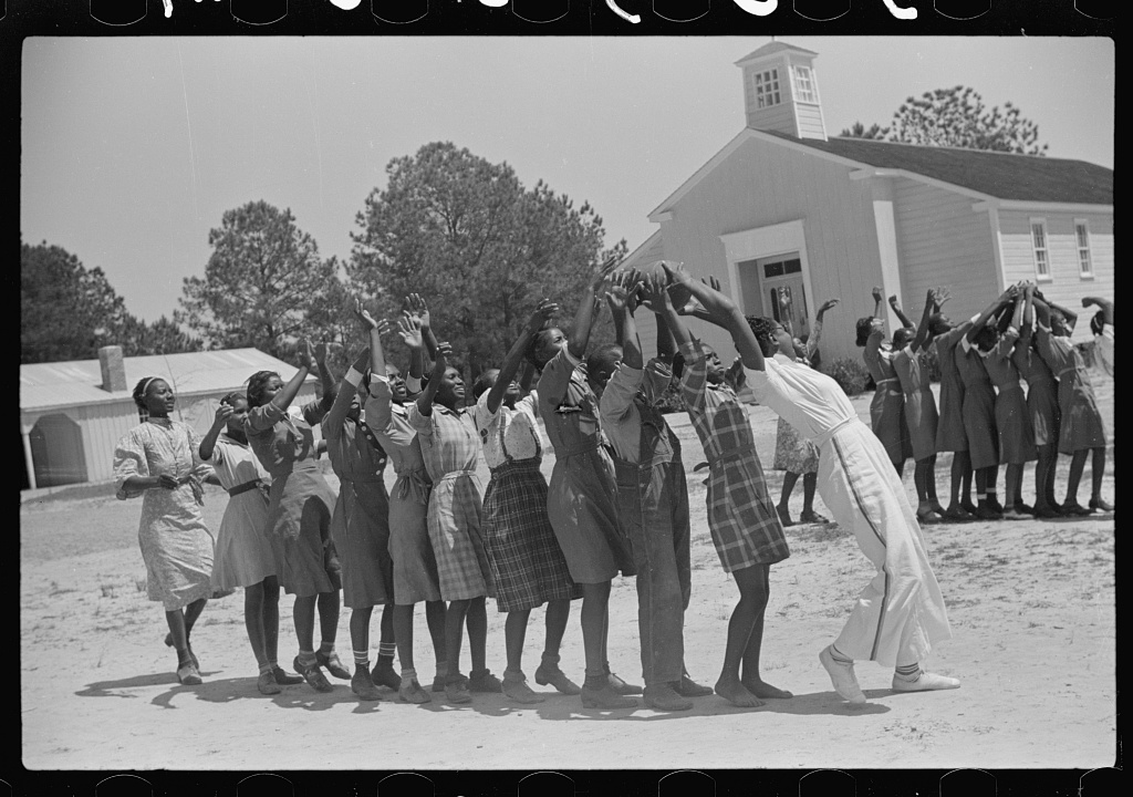 A group of women dancing in a line in a courtyard