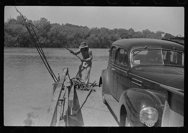 Man steering the landing of a ferry carrying a truck